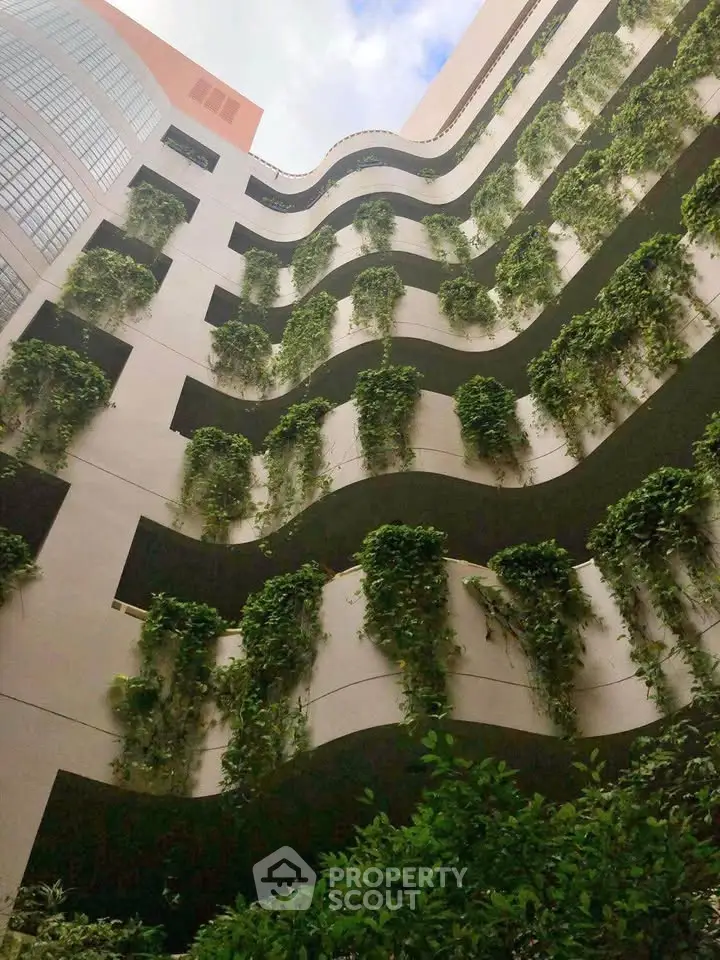 Stunning green facade of modern building with lush vertical gardens and unique architectural design.
