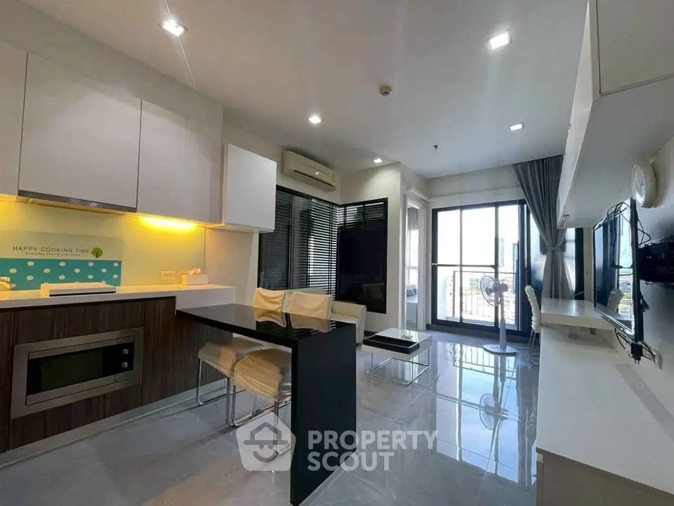 Modern living room with sleek kitchen and balcony view in a stylish apartment.