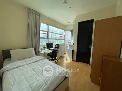 Bright bedroom with city view, featuring a cozy bed and modern workspace.
