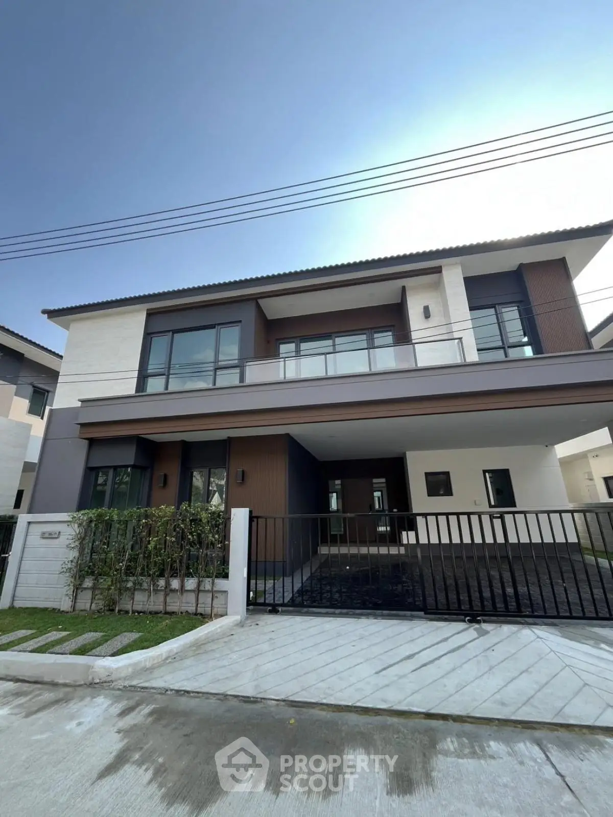 Modern two-story house with sleek design and spacious driveway in a suburban neighborhood.