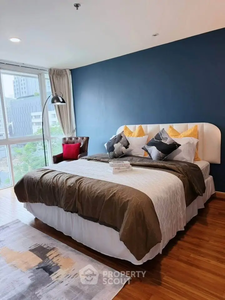Spacious bedroom with modern decor and large window offering city views.