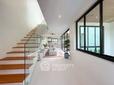 Modern open-plan living room with sleek staircase and large windows