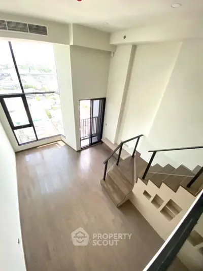 Spacious modern living room with high ceiling and large windows offering natural light
