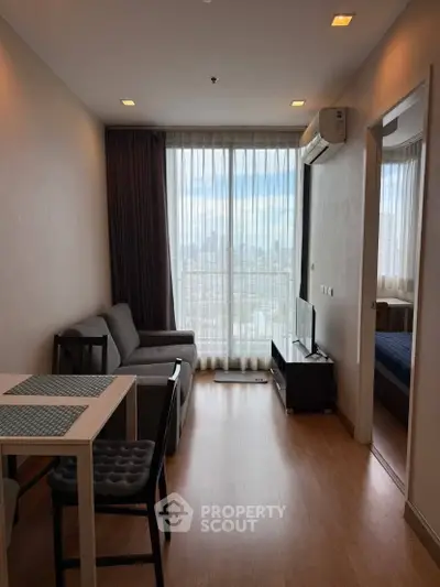 Modern living room with city view, featuring sleek furniture and large windows for natural light.
