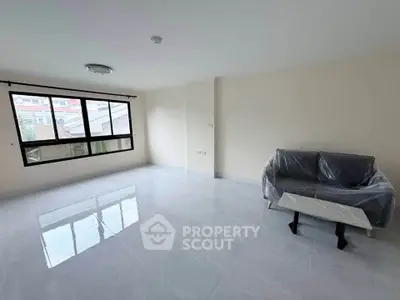 Spacious living room with large window and modern sofa in a bright apartment.