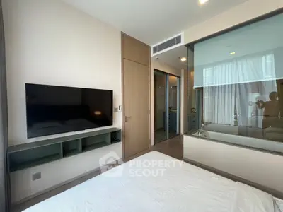 Modern bedroom with wall-mounted TV and glass partition in a stylish apartment.