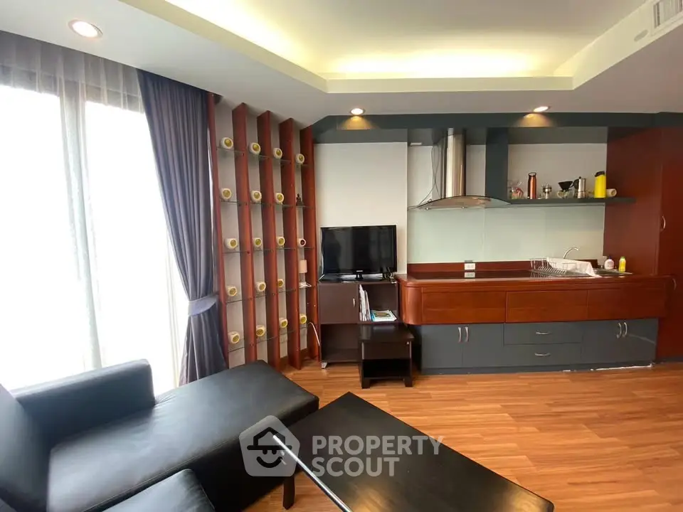 Modern living room with sleek furniture and open kitchen layout, featuring wooden flooring and ample natural light.