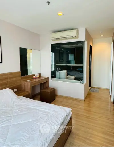 Modern bedroom with glass partition and wooden flooring in a stylish apartment.