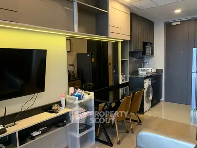 Modern apartment interior with sleek kitchen and cozy living area, featuring a washing machine and stylish decor.