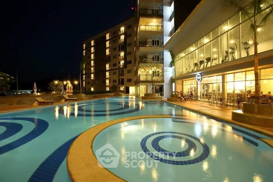 Luxurious apartment complex with illuminated pool and modern architecture at night.
