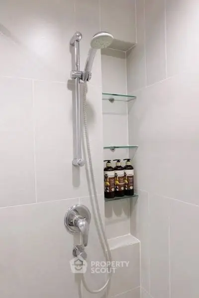 Modern bathroom shower with sleek fixtures and built-in glass shelves.