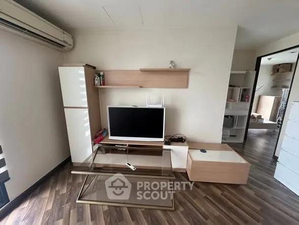Modern living room with sleek furniture and wooden flooring, featuring a TV and stylish shelving.