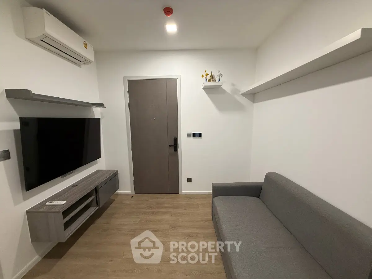 Modern minimalist living room with sleek furniture and wall-mounted TV, perfect for cozy urban living.