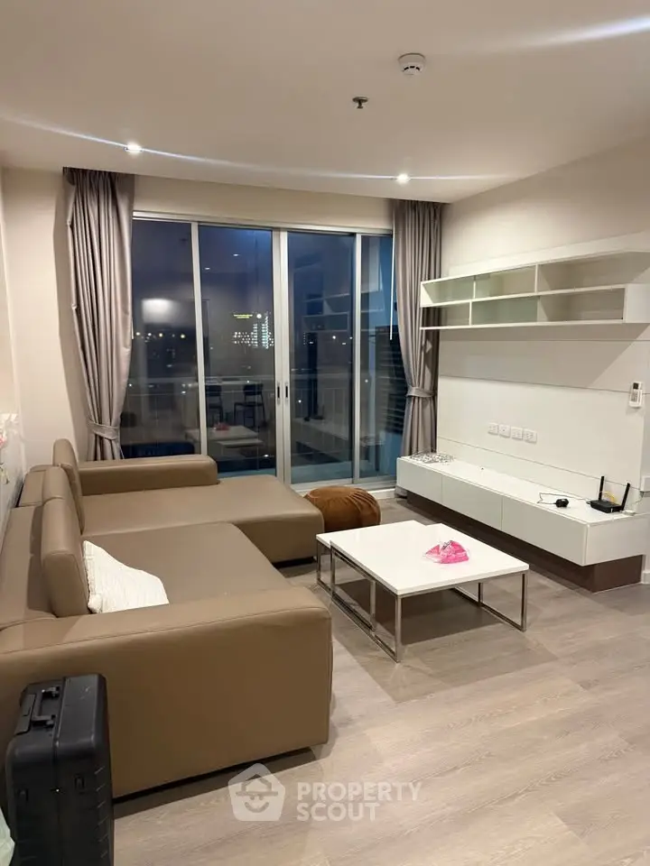 Modern living room with sleek furniture and large windows offering city views.