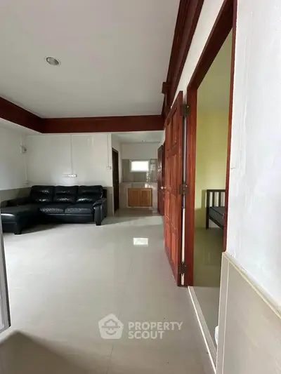 Spacious living area with modern sofa and wooden accents, ideal for family gatherings.