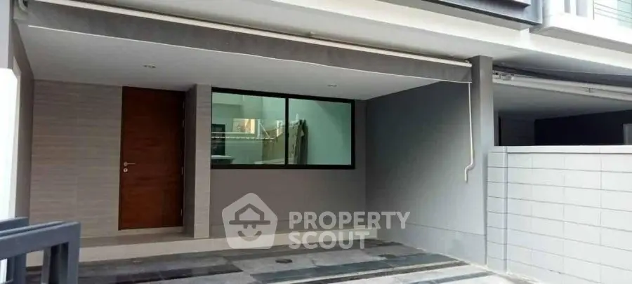 Modern townhouse entrance with covered parking and sleek design.