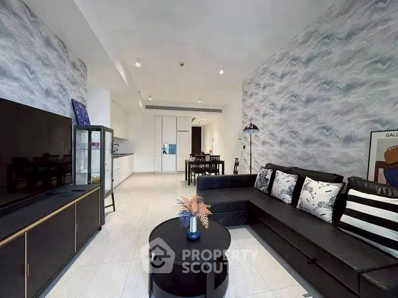 Modern living room with stylish decor and open layout, featuring a sleek black sofa and contemporary furnishings.