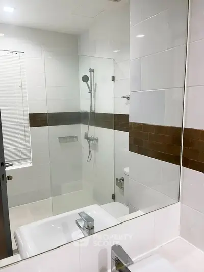Modern bathroom with glass shower and sleek fixtures in contemporary home.