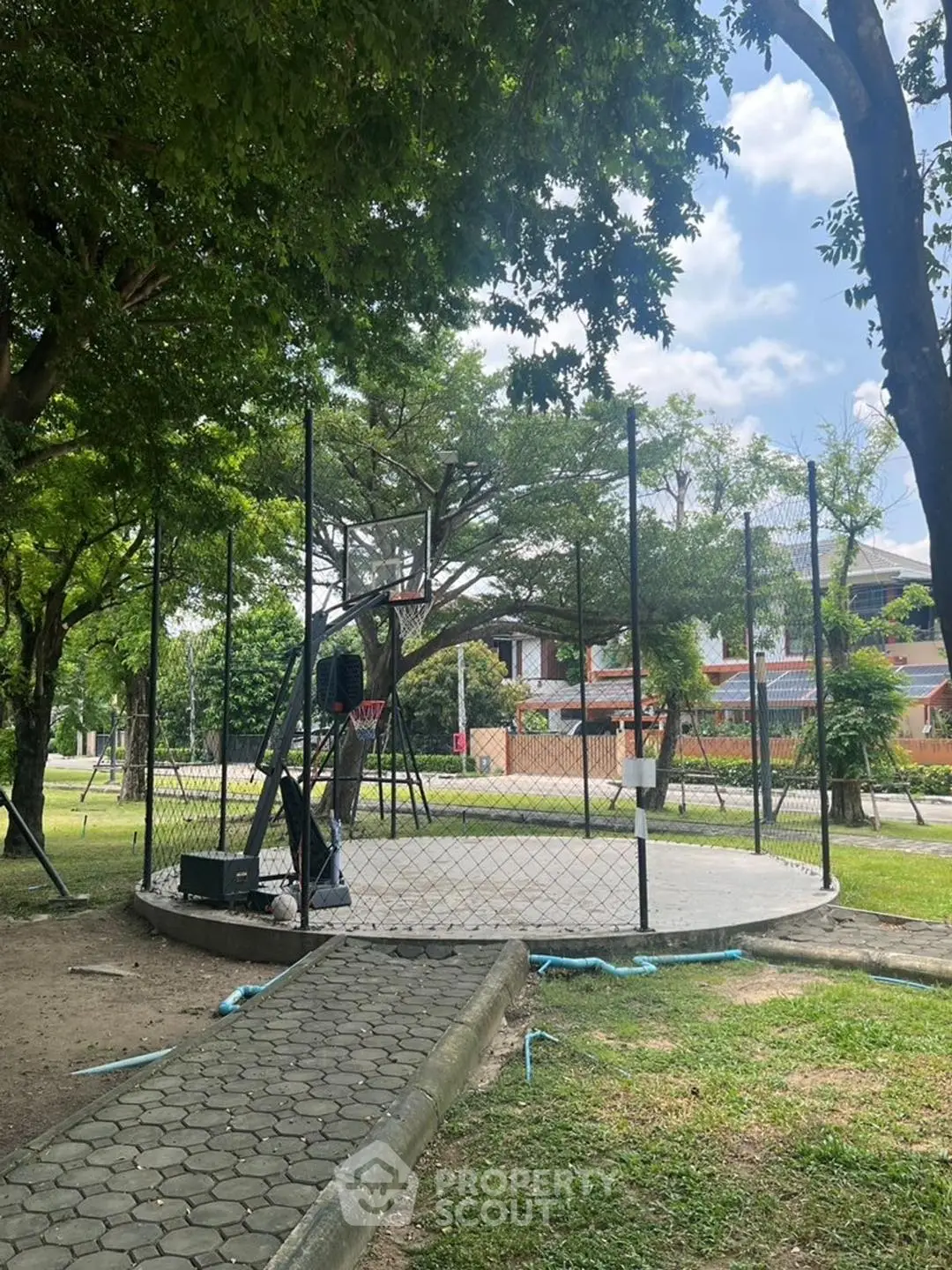 Charming garden view with lush greenery and a fenced circular area, perfect for outdoor activities.