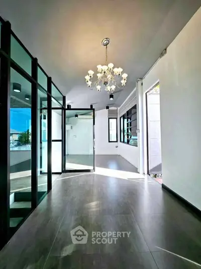 Spacious modern living room with elegant chandelier and glass partitions