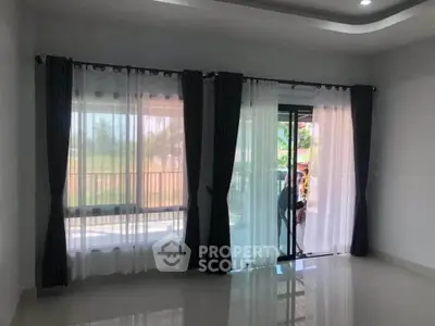 Spacious living room with large windows and elegant curtains, offering abundant natural light and serene views.