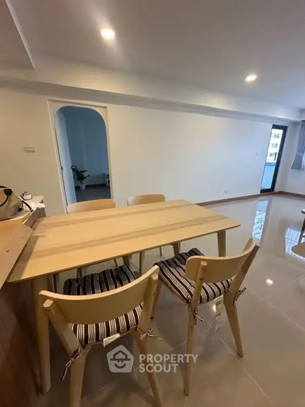 Modern dining area with sleek wooden table and chairs in a spacious apartment.