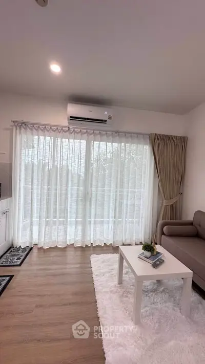 Modern living room with large window, cozy sofa, and stylish decor in a bright apartment.