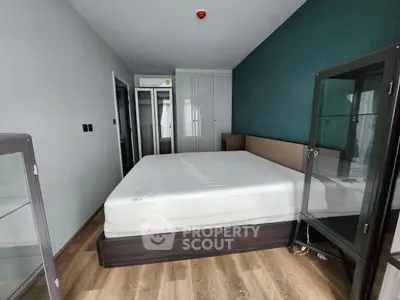Modern bedroom with wooden flooring and glass cabinets, featuring a comfortable bed and stylish decor.