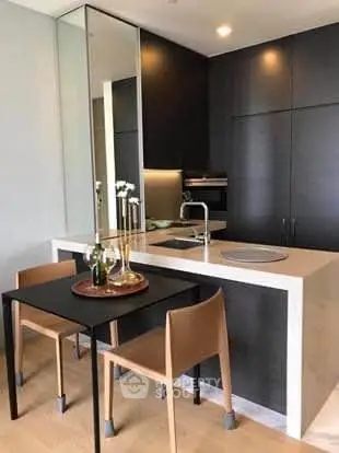 Modern kitchen with sleek black cabinets and compact dining area in a stylish apartment.