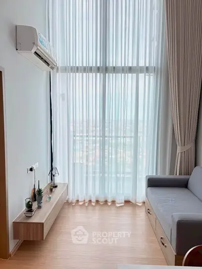 Modern living room with high ceilings, large windows, and stylish decor in a contemporary apartment.