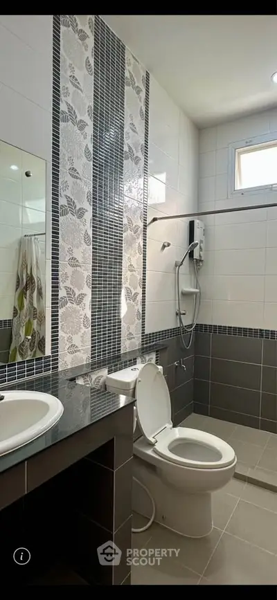 Modern bathroom with stylish tile design and natural light from window.