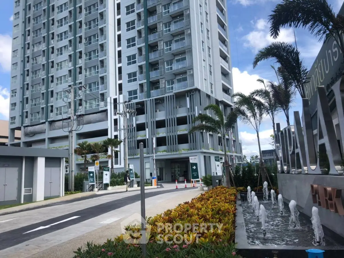 Modern high-rise condominium with lush landscaping and water feature entrance.