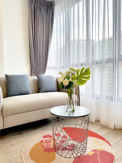 Stylish living room with modern sofa and chic coffee table, featuring large windows and elegant curtains.
