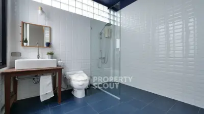 Modern bathroom with sleek glass shower enclosure, white subway tiles, and a classic wooden vanity, offering a blend of contemporary design and traditional charm.