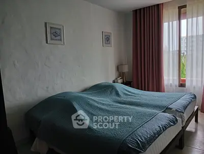 Cozy bedroom with double bed, textured walls, and large window with pink curtains.
