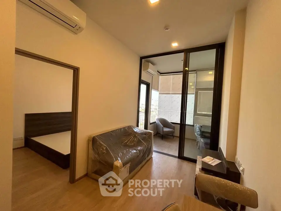 Modern apartment interior with balcony, featuring a cozy living room and bedroom.