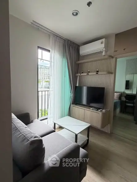 Modern living room with cozy sofa, TV, and natural light from balcony window.