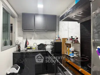 Modern kitchen with sleek black cabinetry and marble backsplash, featuring electric stove and ample storage space.