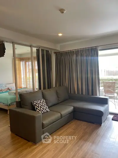 Modern living room with cozy sofa and view into bedroom, featuring stylish wooden flooring.