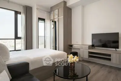 Modern bedroom with city view, sleek furniture, and flat-screen TV.