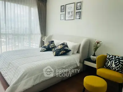 Elegant bedroom with large window, stylish decor, and cozy seating area in modern apartment.