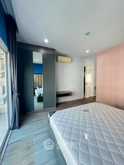 Modern bedroom with large window and stylish decor in a contemporary apartment.