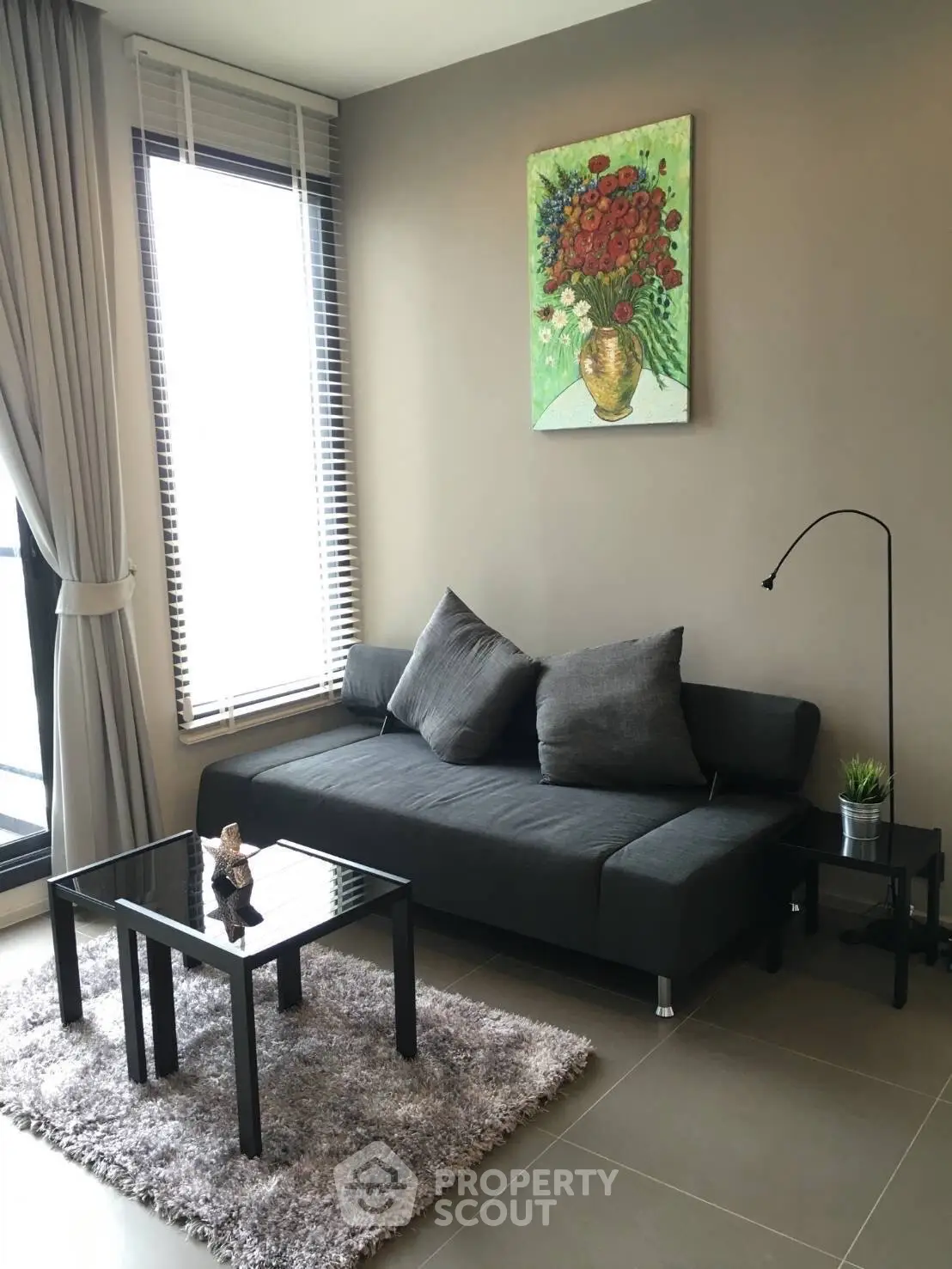 Modern living room with sleek black sofa, glass coffee table, and elegant decor.