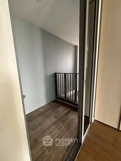 Cozy small balcony with wooden flooring and sleek railing, perfect for relaxation.