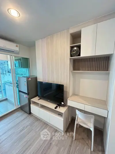 Modern living room with TV, desk, and balcony access in stylish apartment.