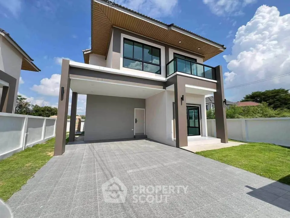 Modern two-story house with spacious driveway and lush green lawn under a clear blue sky.