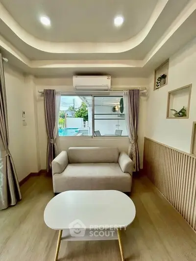 Modern living room with cozy sofa, stylish ceiling, and large window offering natural light.