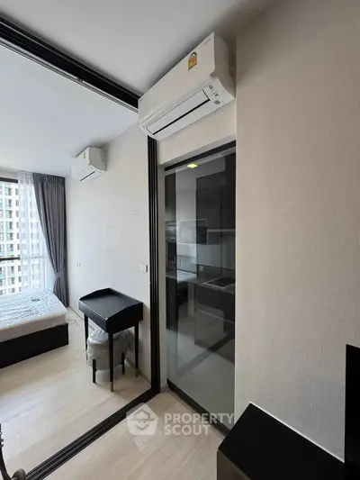 Modern apartment interior with bedroom and kitchen, featuring sleek design and natural light.