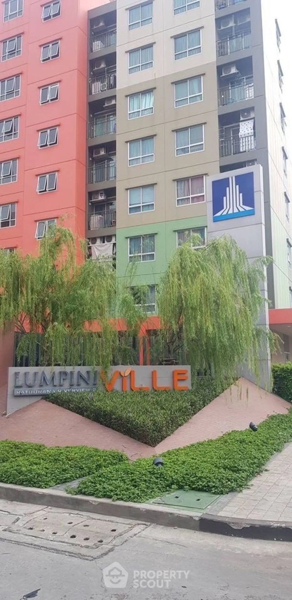 Modern apartment building exterior with colorful facade and lush greenery.