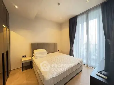Spacious modern bedroom with large window and elegant curtains